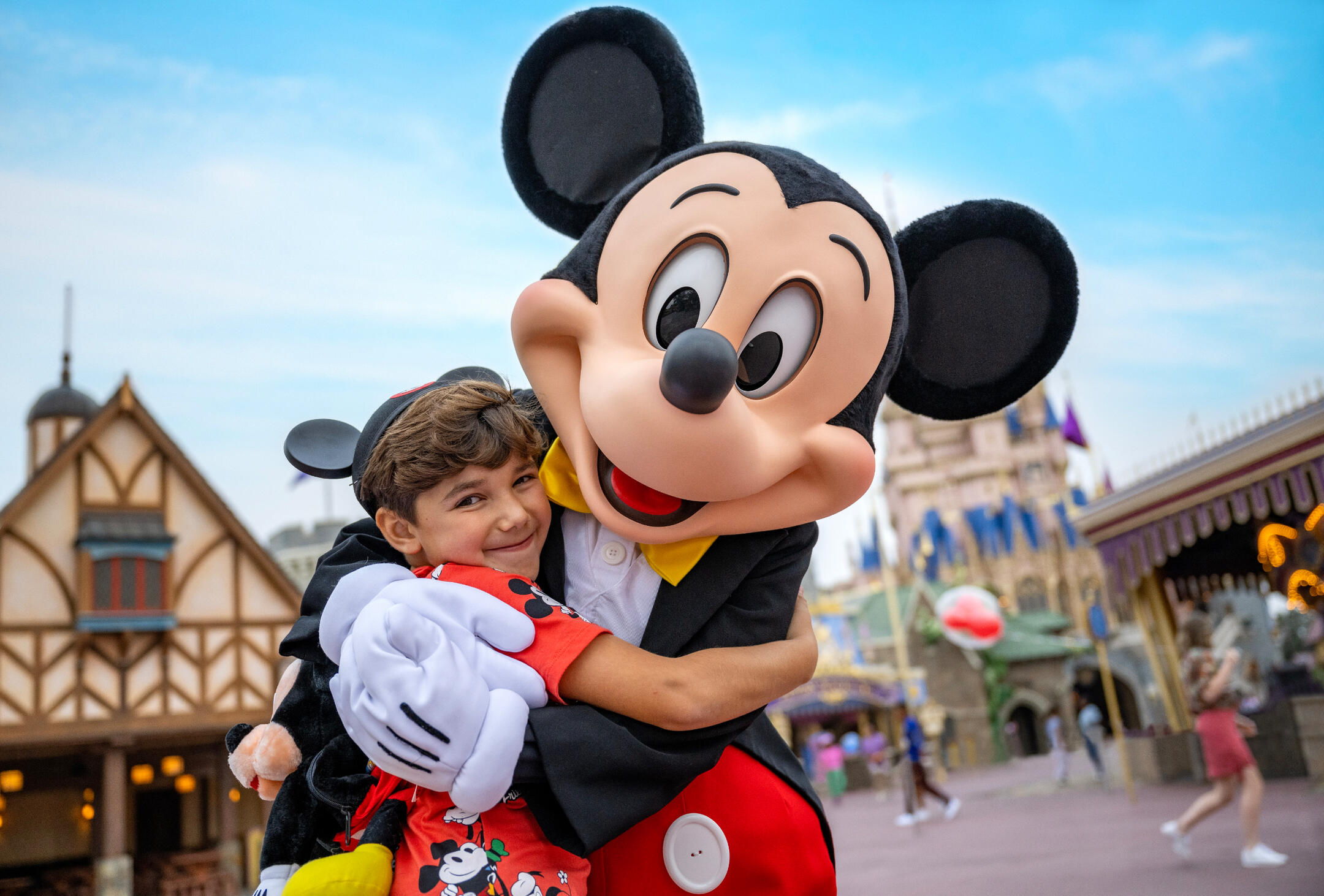 A child wearing Mickey Ears hugs Mickey Mouse while standing in the Magic Kingdom at Walt Disney World Resort in Orlando, Florida.